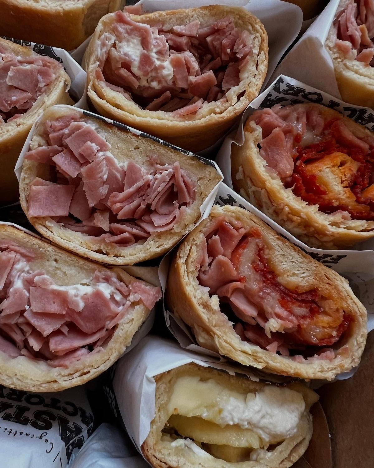 Sándwiches de jamón y queso preparados en casa, envueltos en papel del mercadito