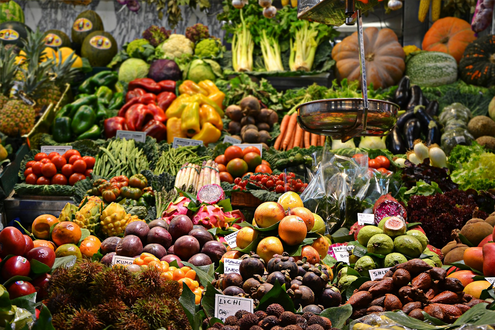 Puesto de frutas y vegetales frescos con piñas, mangos, aguacates y cítricos
