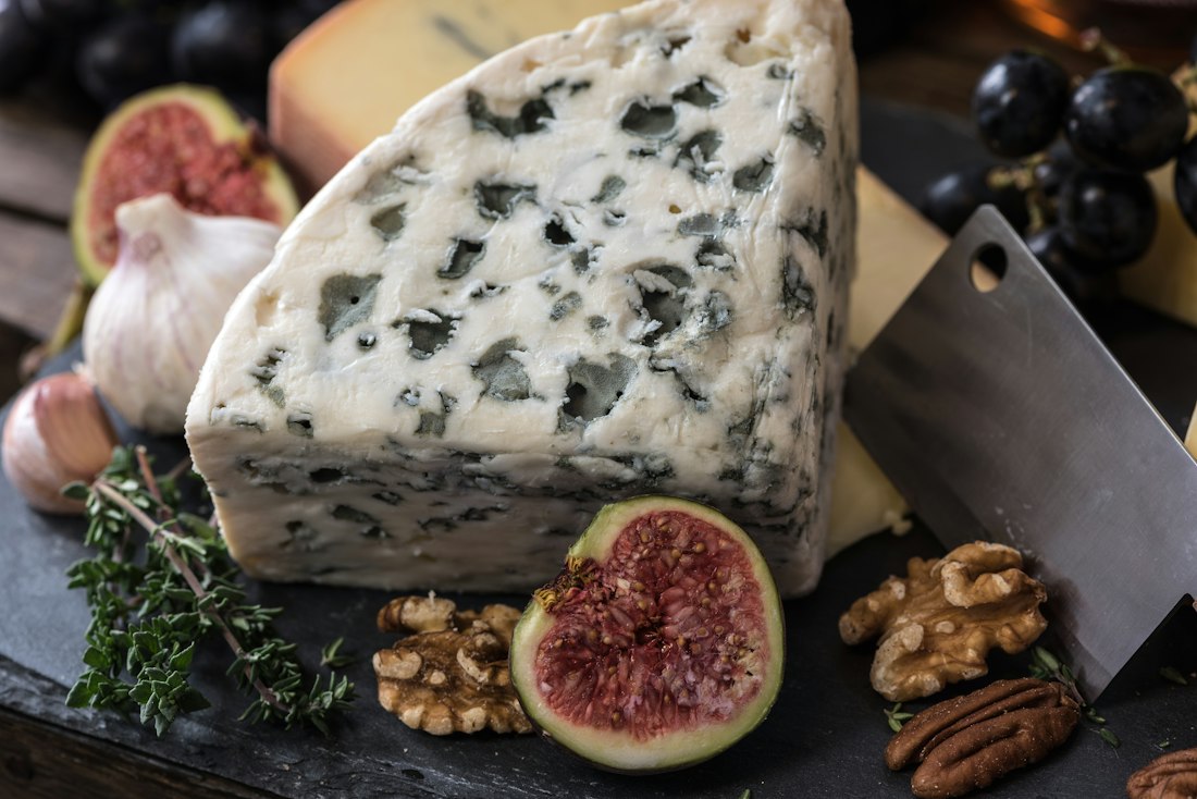 Queso azul con higos, uvas y nueces sobre una tabla