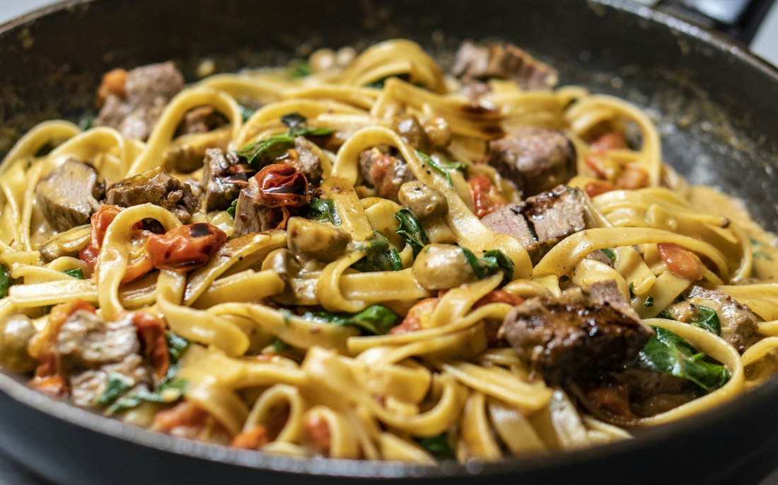 Pasta fresca con champiñones y hierbas en una sartén